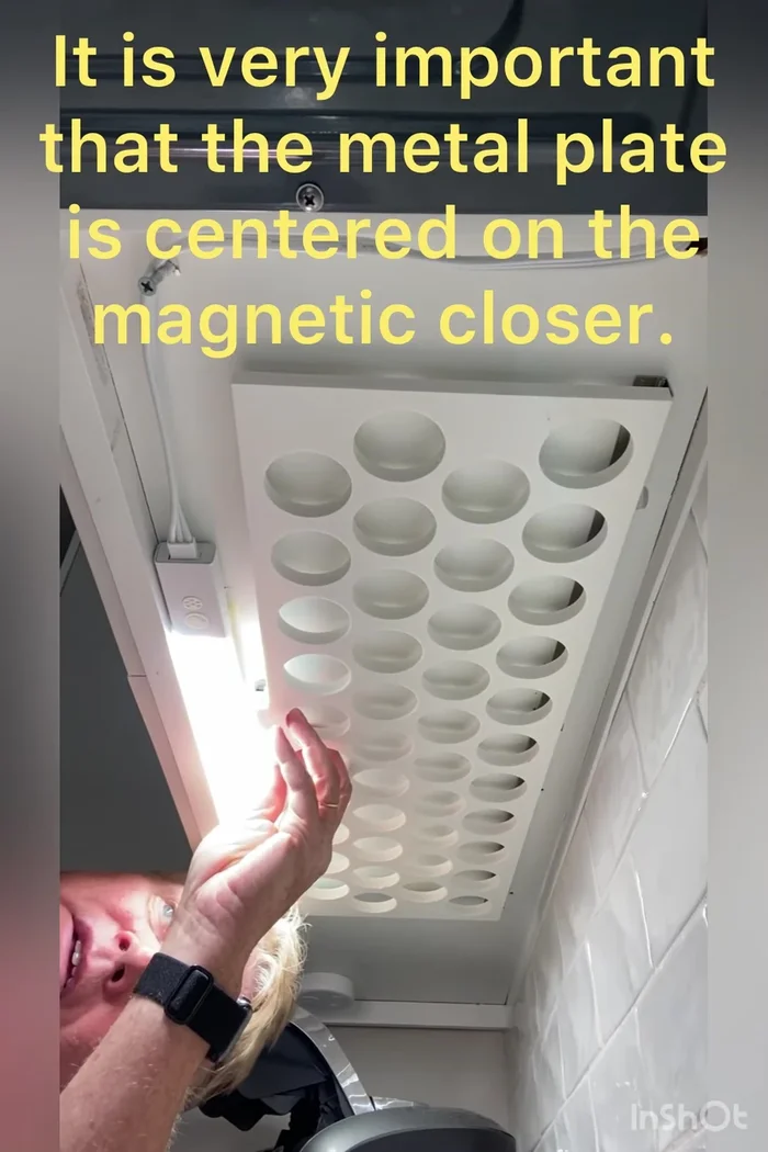 Insert and tighten the small wood screws to secure the metal plate to the cabinet, ensuring flush insertion for maximum magnet contact.