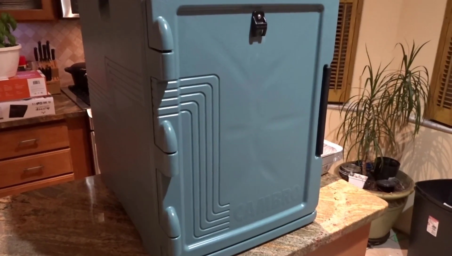 The presenter lifts the larger Cambro container.