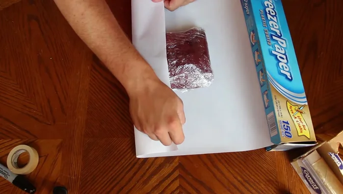 Fold the sides of the freezer paper inwards and tightly over the meat, creating a neat package.