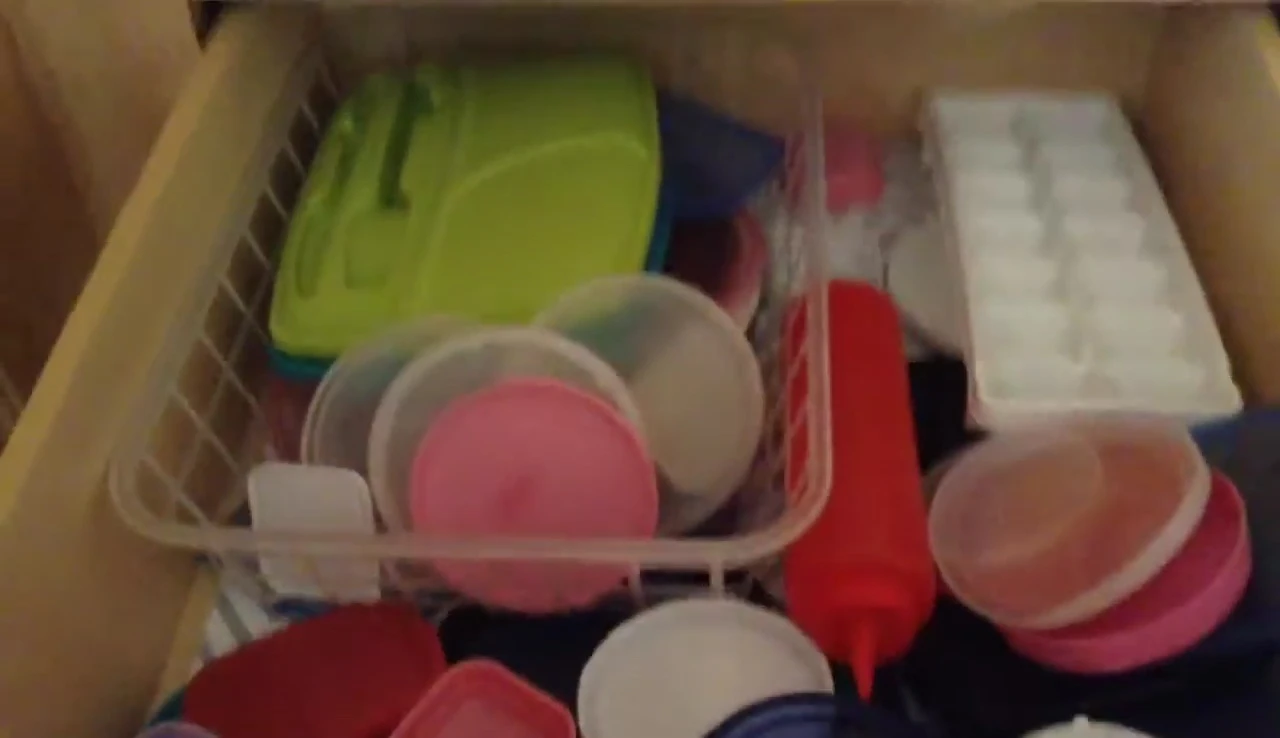 Close-up shot of a drawer overflowing with mismatched containers.