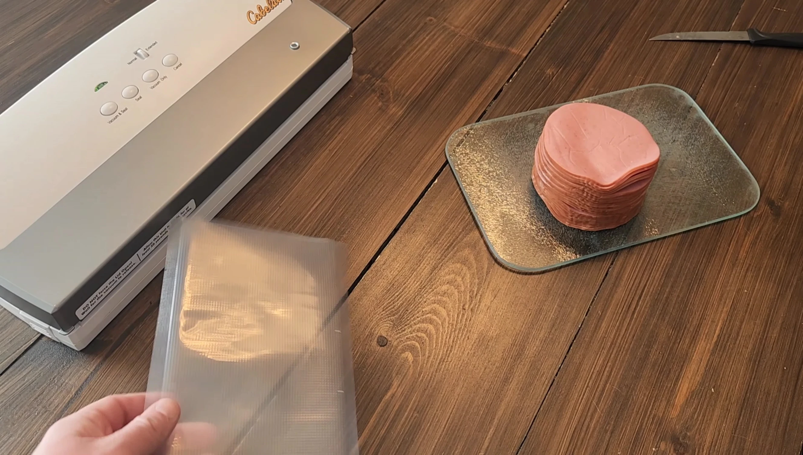 Bologna being placed into a vacuum sealer bag.