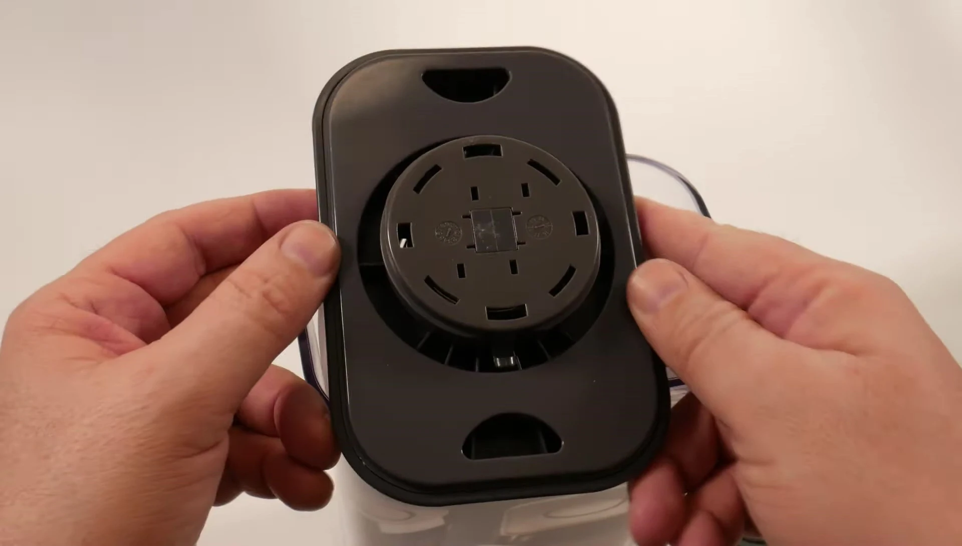 Squeezing the indentations on the lid to remove it.